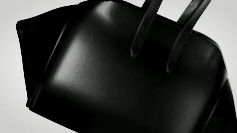 Una borsa di pelle nera in primo piano, con i manici in controluce
