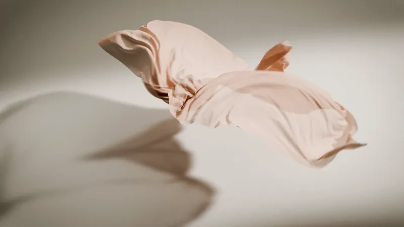 Un tessuto rosa sospeso nell'aria, con la sua ombra sul fondo