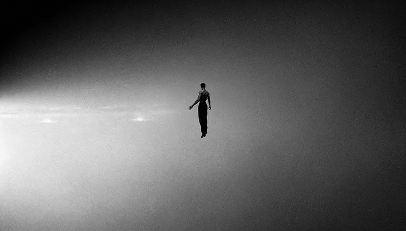 Una figura sospesa nel vuoto, in una luce grigia e granulosa