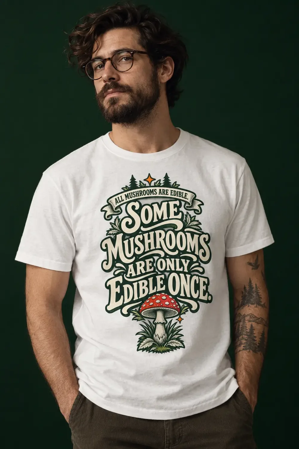 Uomo con una maglia bianca che porta la grafica con funghi e la scritta All Mushrooms Are Edible, But Some Only Once