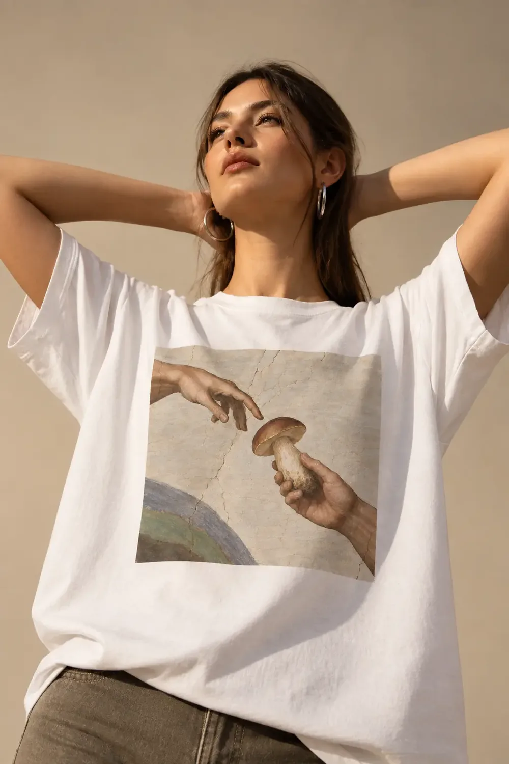 Donna con una maglia bianca che porta La creazione di Adamo reinterpretata con un fungo porcino